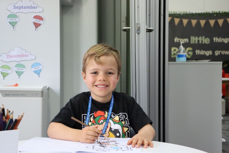 Child sitting at desk colouring in.