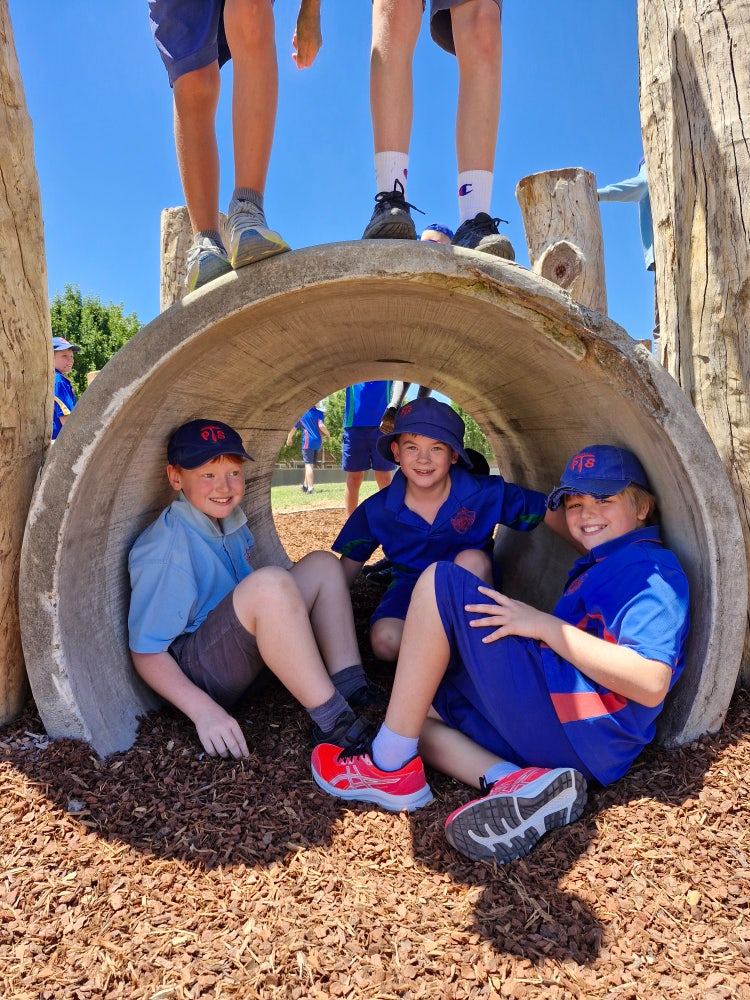 Three boys sitting in tunnel in the playground.