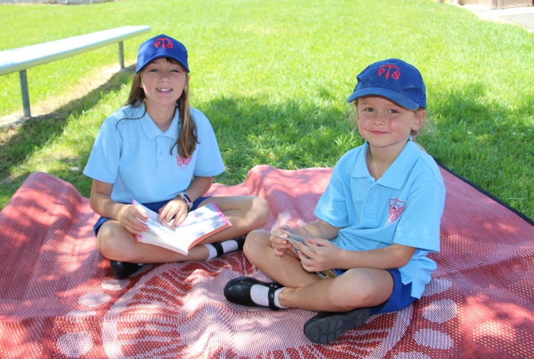 Students reading books outside.