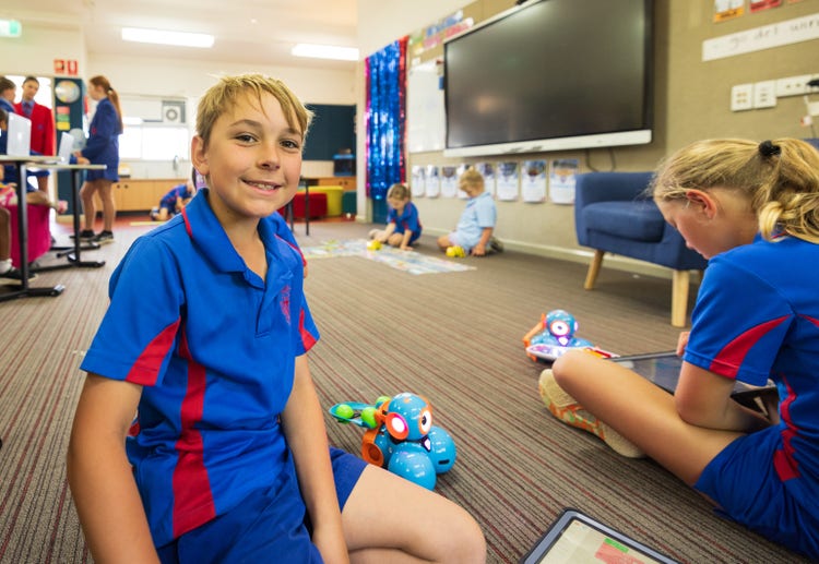 Student playing with a robot in Tech Club.