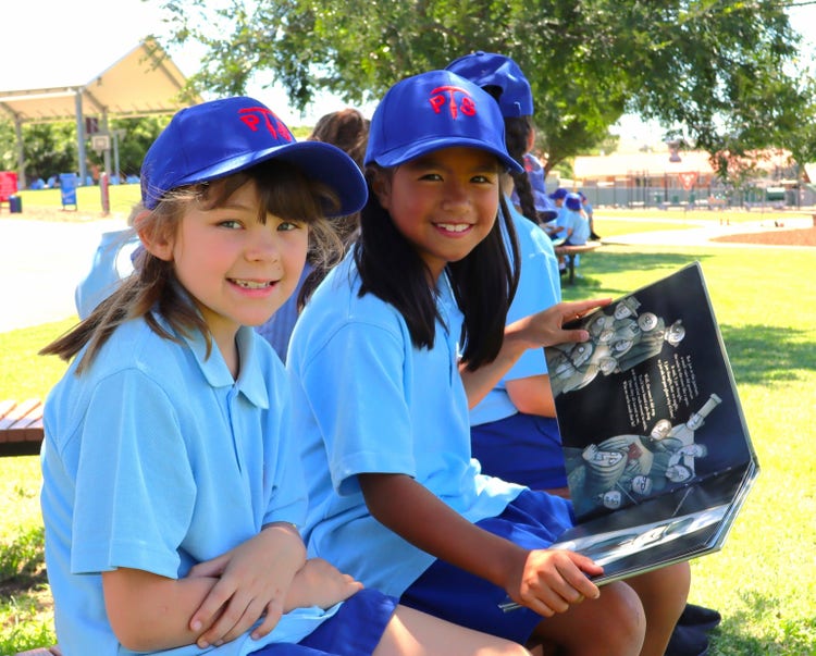 Students reading a book in the playground.