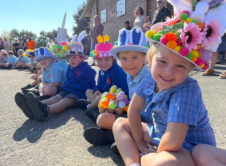 Students proudly sitting with their handmade Easter hats at the school parade.